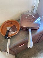 Round fry pan, square pan with lid, utensil visible