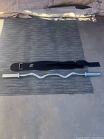 EZ curl bar and lifting belt shown laid out on floor