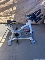 Left side view showing frame, flywheel, handlebars, pedals