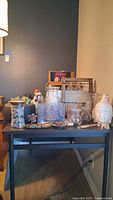 Overall view of table with Buddha head, multiple clear glass vases, faux succulent planter