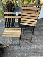 Chairs unfolded and stacked showing wood slat seats/backs and metal frames