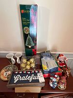Group shot of all items including tree box, ornaments, mugs, lights, sign, plate, figurines
