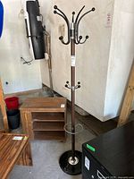 Full view of coat rack showing hooks, pole, umbrella ring, and surrounding context