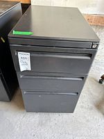 Front view of black metal 3-drawer filing cabinet with lock