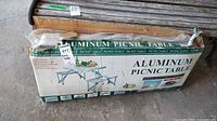 Boxed aluminum picnic table showing item and packaging