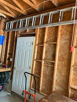 Full ladder stored horizontally along wall above door