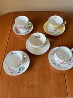 Five teacups each with matching saucer displayed on table