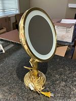 Front view showing mirror surface, light ring, brass stand and cord