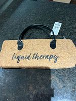 Front view showing cork exterior, 'liquid therapy' text, handles