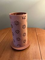 Terracotta perforated candle sleeve on base, full view