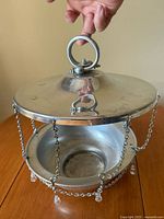 Overall view of hanging bowl with lid held up, showing chains and pendants