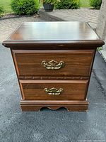 Front view of nightstand showing two drawers, brass-tone handles, dark brown finish