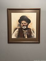 Full view of framed sad clown artwork on wall