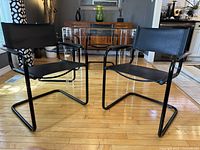 Front angle view of both black leather cantilever chairs