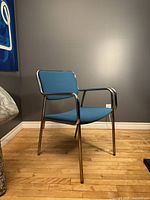 Front angled view of chrome armchair with blue upholstery