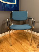 Front view of tubular chrome armchair with blue upholstery