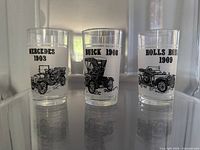 Three glasses showing Mercedes 1903, Buick 1908, Rolls Royce 1909 designs