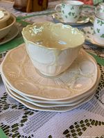 Stack of four Belleek shell pattern plates with matching teacup on top