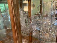 cabinet shelf with etched crystal pitcher, small pitchers, cordial glasses, platter