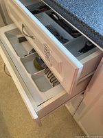 Open drawers showing utensil tray with citrus press and potato masher