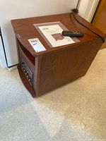 Full view of LifeSmart wood-cabinet heater with remote and manual on top