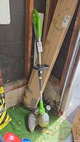 Full view of Greenworks corded trimmer leaning against wall