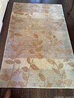Full view of rectangular beige-taupe rug with vine motif
