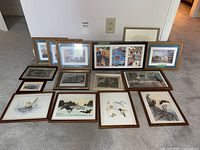 All fifteen framed artworks grouped on floor showing variety of sizes and subjects