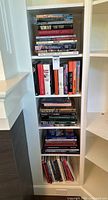 Full view of narrow built-in shelving unit holding five shelves of assorted hardcover books