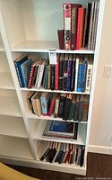 Five shelves of assorted books in white bookcase