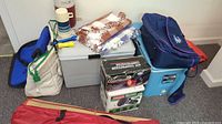 Overall view of camping gear lot including coolers, blankets, boxed items and bags