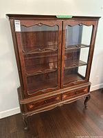 Front view showing glass doors, shelves, drawers, cabriole legs