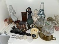 Shelf with multiple figurines, candles, stone pieces, glass holders, and vase