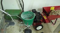 Red Lawn Chief chipper/shredder with attached spreader and green lawn roller beside