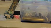 Brass door handle set, boxed fluorescent bulb, pink note, clear bin with brass lighting pieces and glass shades