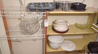 Overview of shelves showing punch bowl set, muffin pan, mixing bowl, square pan, casserole, green glass bowl, salad spinner, red plate