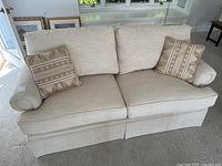 Front view of beige loveseat with two pillows
