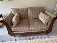 Front view of striped upholstered loveseat with wood frame and cushions