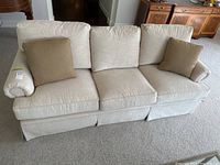 front view of three-seat beige sofa with two pillows