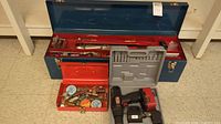 Overall view showing both toolboxes, open with contents, and the cordless drill in its case
