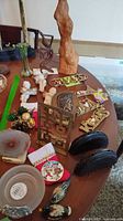 Overview of lot on table showing wood sculpture, key racks, brass plaque, cherubs, coin purses, ornaments, geode