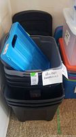 Stack of black, grey and blue bins with blue folding crate visible