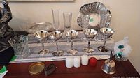 Overall view of silver-plated coupes, dishes, glass vases, bell and candles