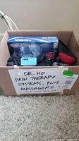 Box containing Dr. Ho system packaging, handheld massager and additional items