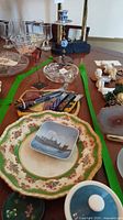Overview showing plates, cheese board with spreaders, cut glass dish, candlestick with blue accent, metal flower