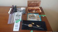 Group shot showing all items on table: sterling clip container, watches, chains, Hickies pack, plastic shoelaces