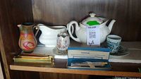 Shelf view showing all ceramic pieces, cup & saucer, pens and pen case
