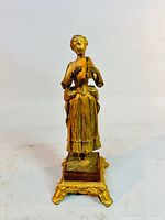 Front view of gilded woman figurine on ornate base