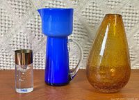 Group shot of tealight holder, blue pitcher and amber vase