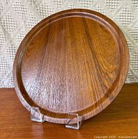 Front view of teak charger plate on clear stand
